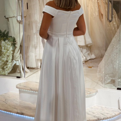 Vestido branco de noiva acetinado com corte ombro a ombro em loja de noivas