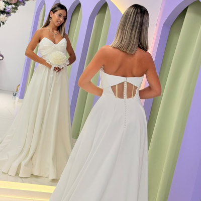 Vestido de noiva branco com detalhes de botões visto de costas refletido num espelho em moldura lilás