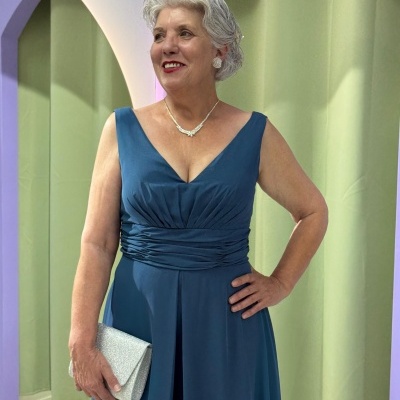 Mulher vestindo vestido azul sem mangas e segurando clutch prateada