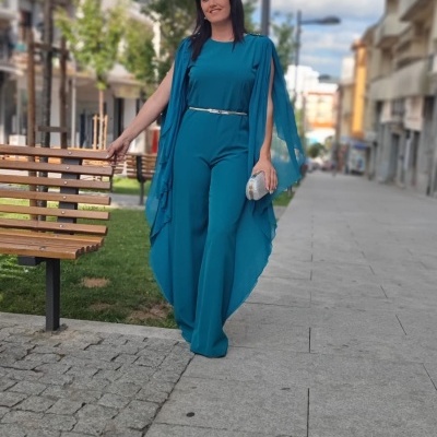 Mulher com macacão azul turquesa com cinto prateado num passeio urbano