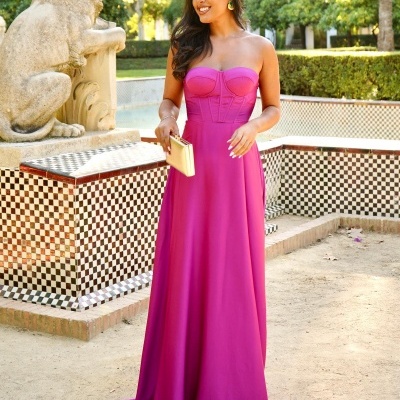 Vestido longo tomara que caia rosa fúcsia com carteira dourada em jardim