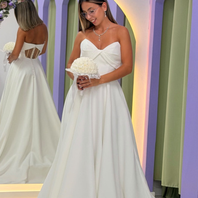Vestido de noiva branco tomara que caia com recortes e botões nas costas, mulher com bouquet branco e acessórios cristais