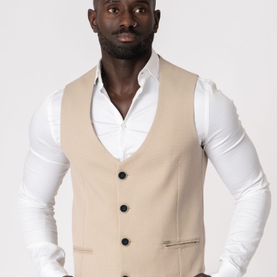 Colete masculino bege com botões pretos sobre camisa branca de manga comprida