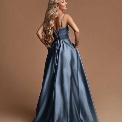 Vestido longo azul acetinado visto de costas, com alças finas e amarração nas costas, em fundo castanho.