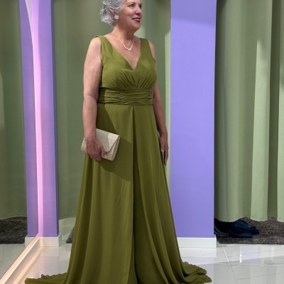 Vestido longo verde-oliva com carteira bege e fundo lilás e cortinas verdes