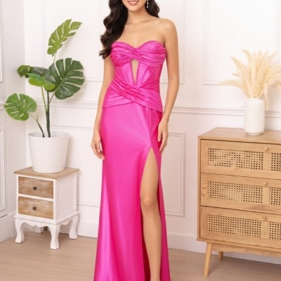 Mulher com vestido longo fucsia acetinado com fenda alta em ambiente interior