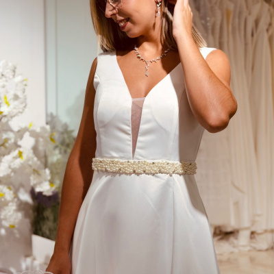 Vestido de noiva branco com faixa de pérolas e ramo de flores brancas