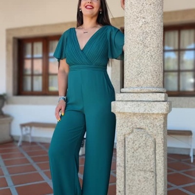 Mulher vestindo macacão verde com mangas curtas e calças largas em ambiente exterior