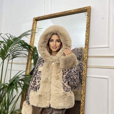 Casaco bege de pêlo sintético com capuz largo e padrão de leopardo nas mangas, mulher posando em frente a espelho dourado