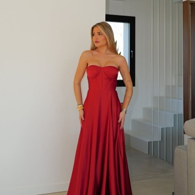 Mulher com vestido longo vermelho com corpete sem alças em sala moderna