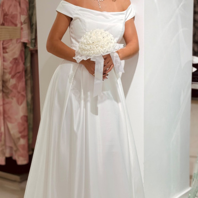 Mulher com vestido de noiva branco e bouquet branco em cenário interior
