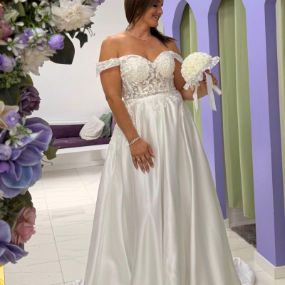Vestido de noiva branco bordado com bouquet em ambiente com arcos lilás e flores artificiais