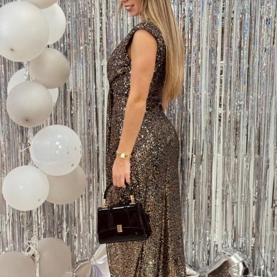 Mulher a usar vestido brilhante prateado com sapatos pretos e mala, fundo prateado e balões brancos