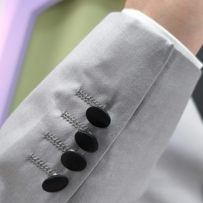 Manga de fato cinzento claro com botões pretos