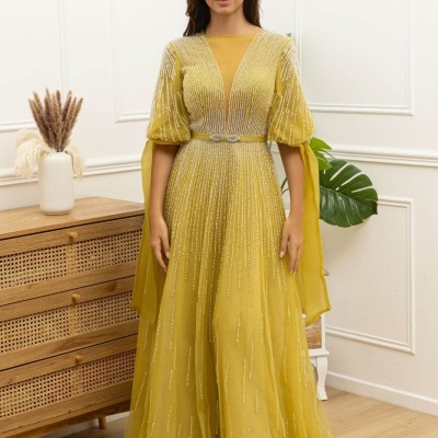 Vestido longo amarelo com tule e lantejoulas prateadas em ambiente interior