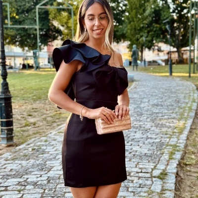 Vestido preto curto com babados e mala rosa metálica ao ar livre