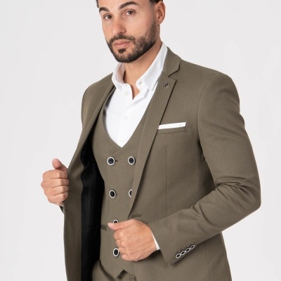 Homem a usar fato verde-oliva com colete e camisa branca.