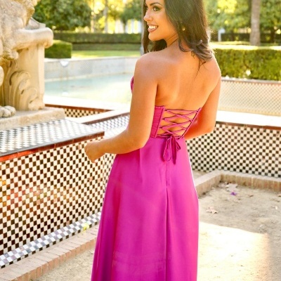 Vestido longo rosa com costas abertas e amarração em ambiente exterior com jardim e azulejos pretos e brancos