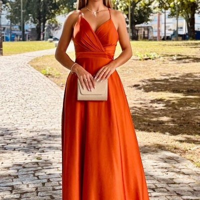 Mulher com vestido comprido laranja e óculos num parque