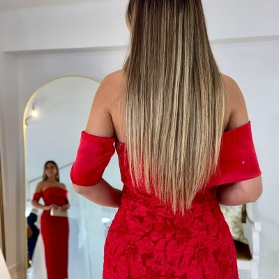 Vestido vermelho justo com padrão floral e mangas curtas ombro a ombro visto de costas junto a espelho