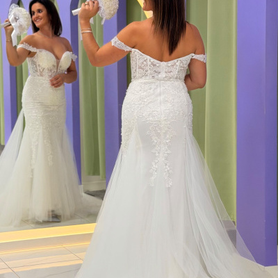 Vestido de noiva branco com rendas e tule e decote ombro a ombro, refletido num espelho