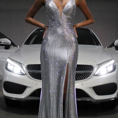 Vestido longo prateado com lantejoulas e decote em V frente a carro branco