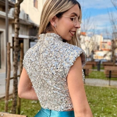 Blusa cropped prateada com lantejoulas e saia azul metálica em ambiente urbano