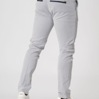 Calças cinzentas claras justas usadas com sapatilhas brancas e cinto preto trançado