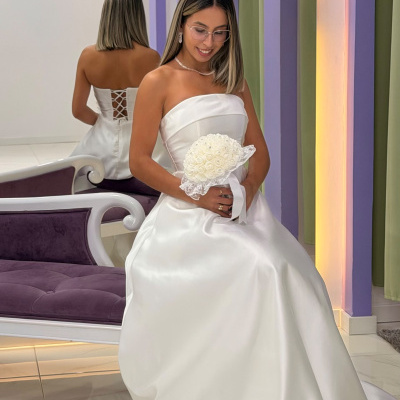 Vestido de noiva branco com bouquet e banco roxo em estúdio decorado com arco e flores.
