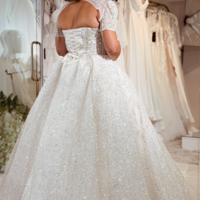 Vestido de noiva branco com brilhos e mangas curtas transparentes num provador