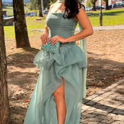 Mulher com vestido longo verde azul e clutch azul brilhante ao ar livre