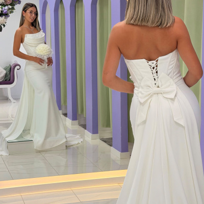 Vestido de noiva branco com laço atrás refletido num espelho num ambiente com arcos lilás