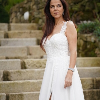 Mulher com vestido de noiva branco posando em escadaria de pedra