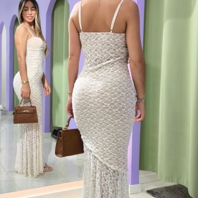 Vestido comprido de renda branco com alças finas numa sala com paredes lilás e cortinas verdes