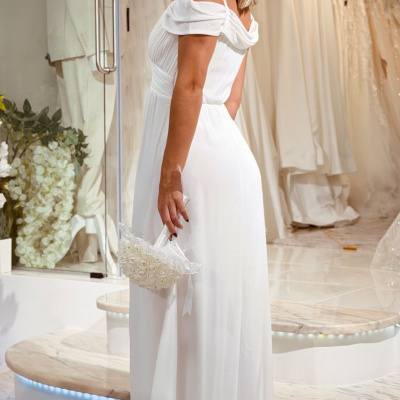 Vestido branco longo com alças e decote ombro caído numa loja de vestidos de noiva