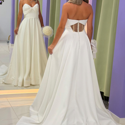Vestido de noiva branco com saia ampla e corpete tomara que caia em loja com decoração lilás