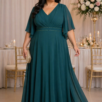 Vestido comprido verde escuro com mangas curtas e detalhes dourados, mala e sandálias douradas em ambiente festivo