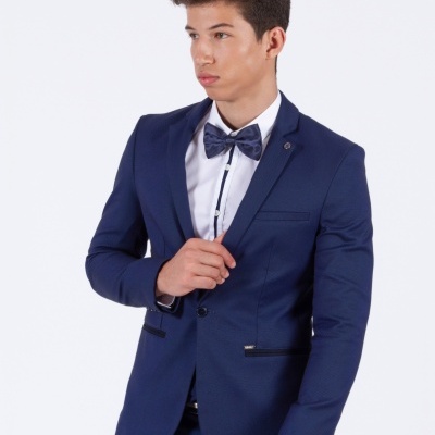 Homem jovem com fato azul escuro, camisa branca e gravata borboleta azul