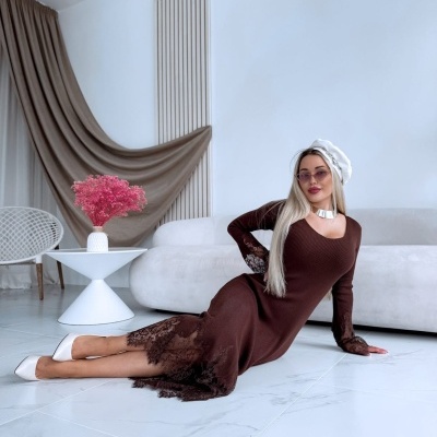 Mulher deitada em chão branco com vestido castanho comprido com renda e sapatos brancos