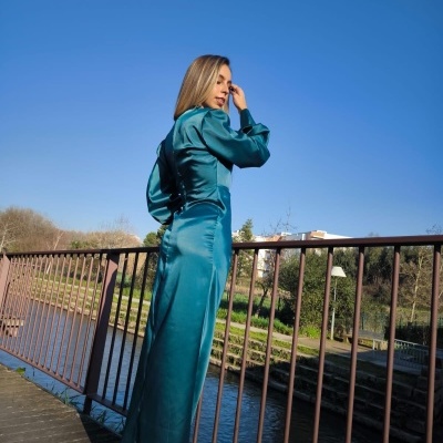 Mulher com roupa azul de cetim junto a rio numa ponte