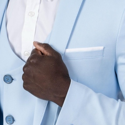 Paletó azul claro com camisa branca e mão fechando o casaco.