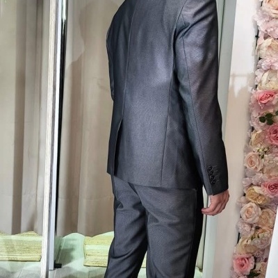 Homem de costas com fato cinzento e sapatos brancos em ambiente interior