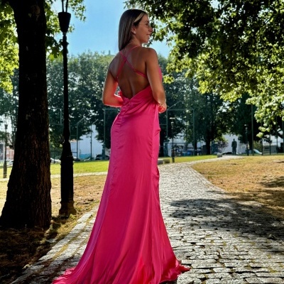 Vestido comprido cor-de-rosa com alças finas cruzadas visto de costas num passeio com árvores