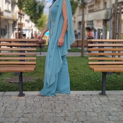 Mulher com macacão azul claro e óculos de sol num parque urbano