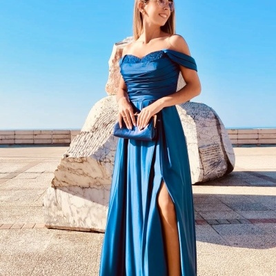 Mulher com vestido azul longo e clutch azul em ambiente exterior