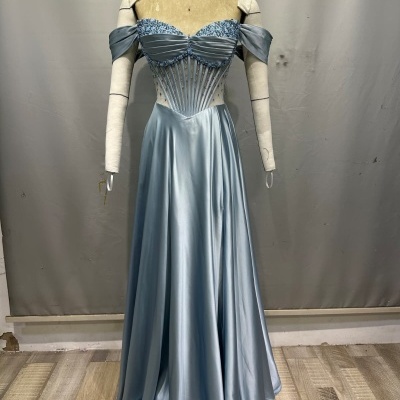 Vestido azul claro de cetim com corpete transparente e mangas caídas num manequim.