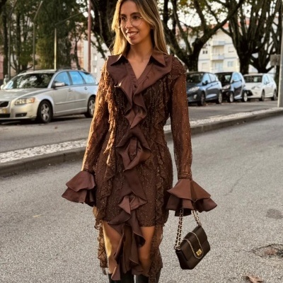 Mulher com vestido castanho com folhos e botas pretas a andar na rua