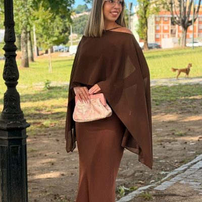 Mulher com vestido castanho longo e mala rosa em parque