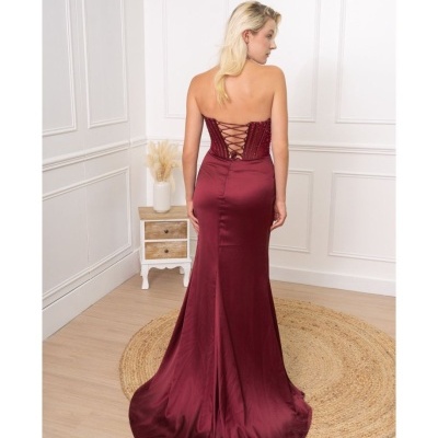 Vestido longo bordô com corpete bordado e cadarço nas costas, modelo de costas em sala interior