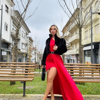 Mulher com vestido vermelho e casaco preto numa praça urbana